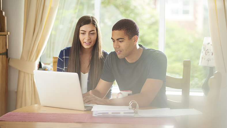 Young couple sitting together at laptop.