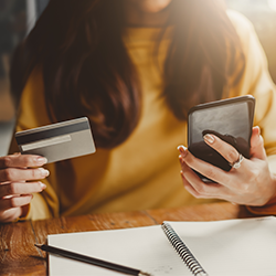 Woman holding debit card and mobile device